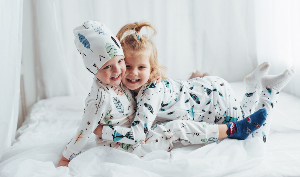 Children in soft warm pajamas playing in bed