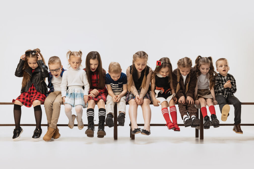 group-children-wearing-stylish-cloth-sitting-bench-posing-isolated-grey-studio-background